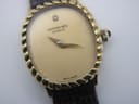 Close-up of the champagne dial, showing Raymond Weil logo, single diamond marker, gold hands, and subtle crystal scratches.