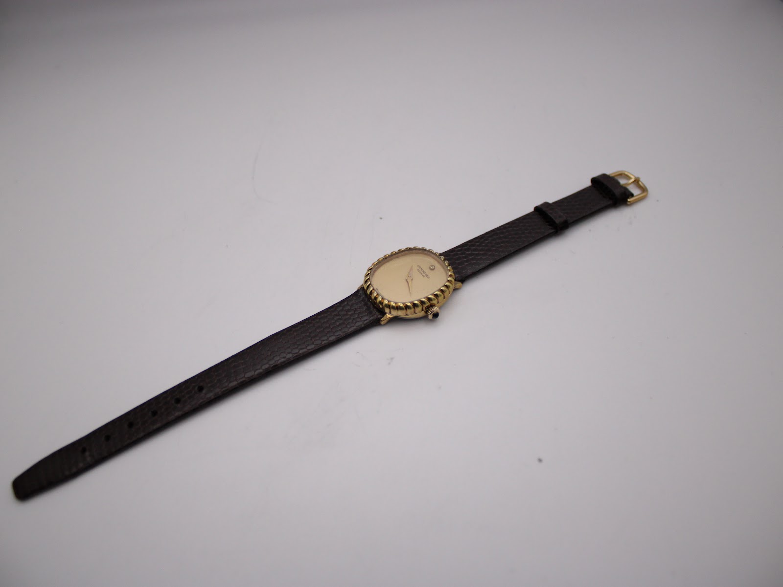 Full length view of the Raymond Weil watch and dark brown leather strap, lying flat against a white background.