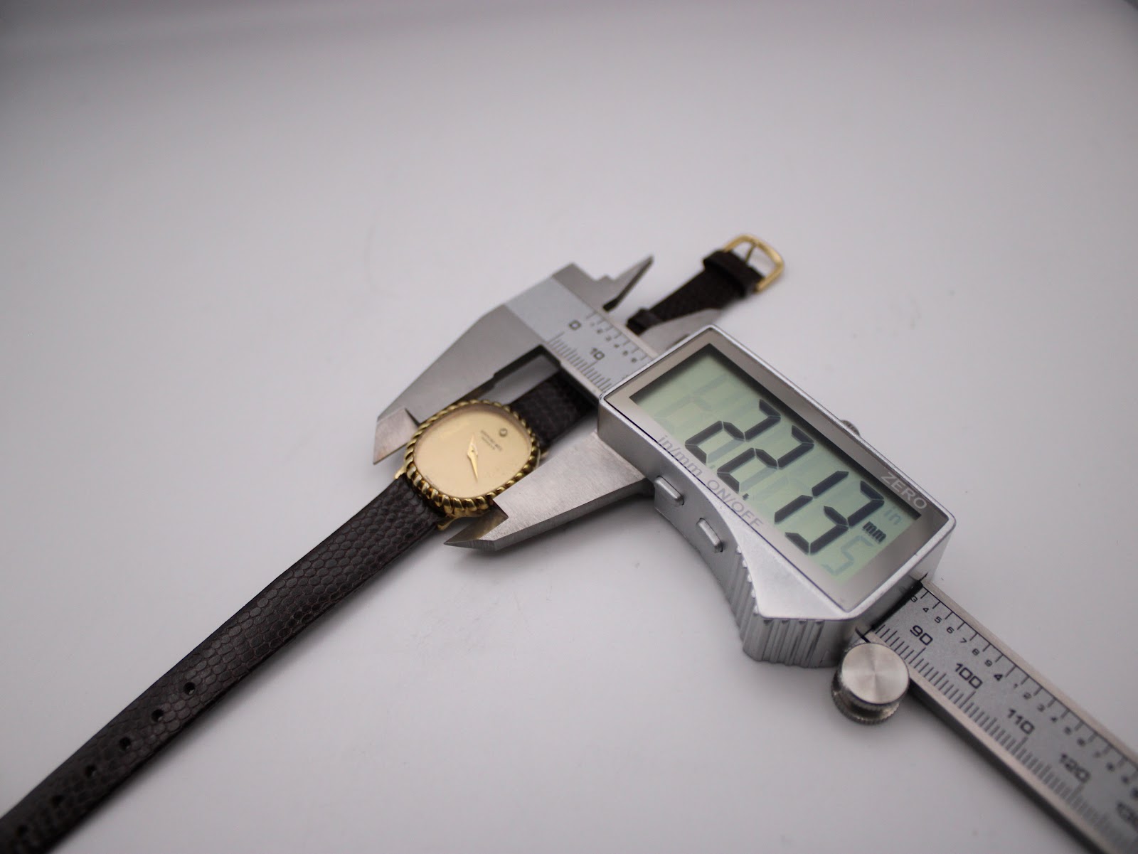 Digital caliper measuring the width of the Raymond Weil watch case at 22.13mm, positioned next to the watch.