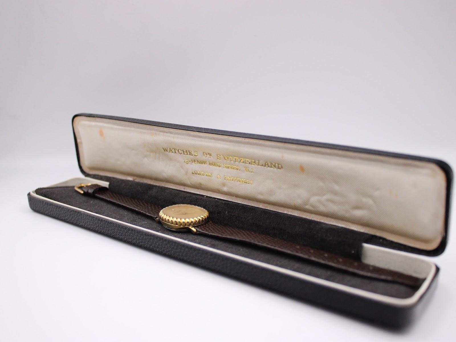 The Raymond Weil watch resting inside a vintage 'Watches of Switzerland' presentation box.