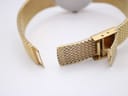 Close-up of the adjustable fold-over clasp on the gold mesh bracelet.