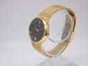 Three-quarter angled view of the Accurist watch on a clear display stand, highlighting the gold case and mesh bracelet.