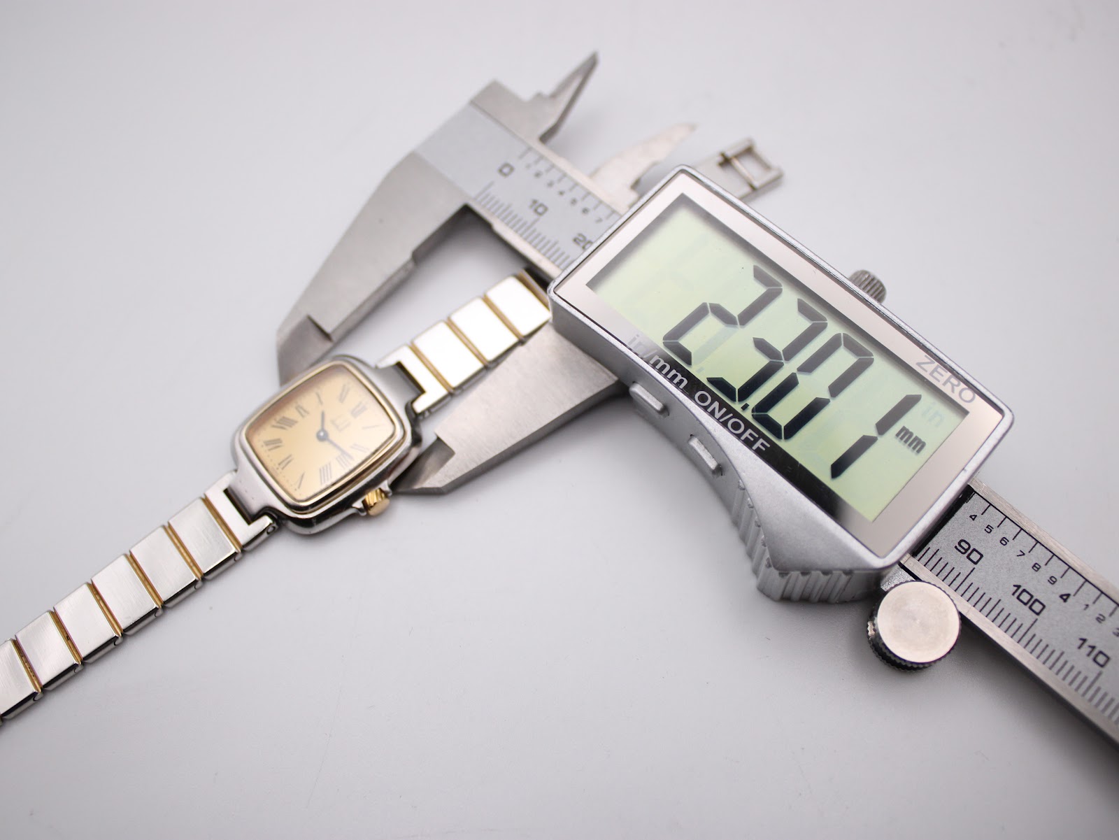 Digital caliper measuring the watch case, displaying a precise diameter of 23.07mm.