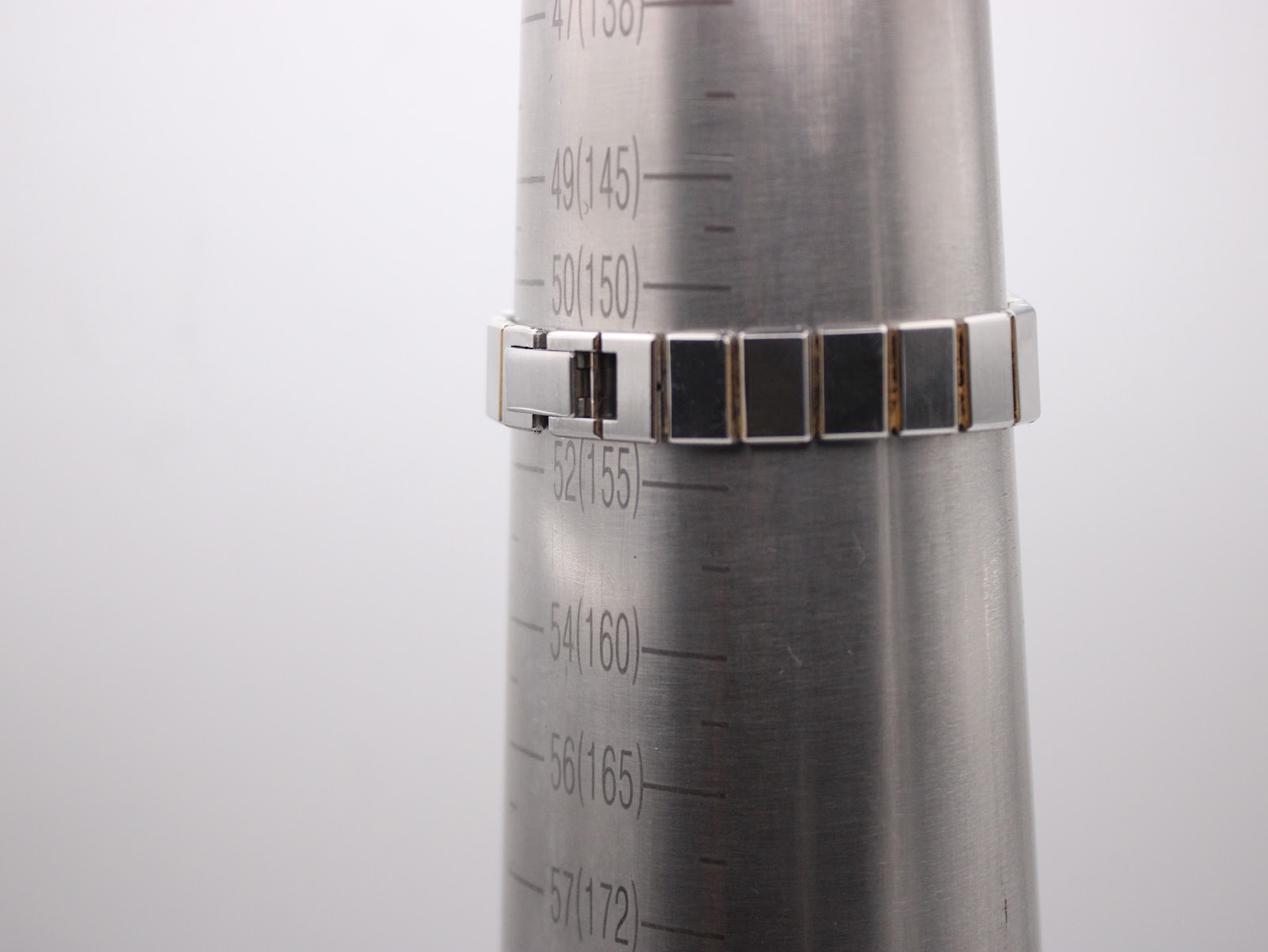 Watch bracelet on a wrist sizing cone, showing a circumference measurement of 155mm.