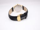 Close-up of the gold-tone deployant clasp, closed on the black leather strap, showing its sleek design.