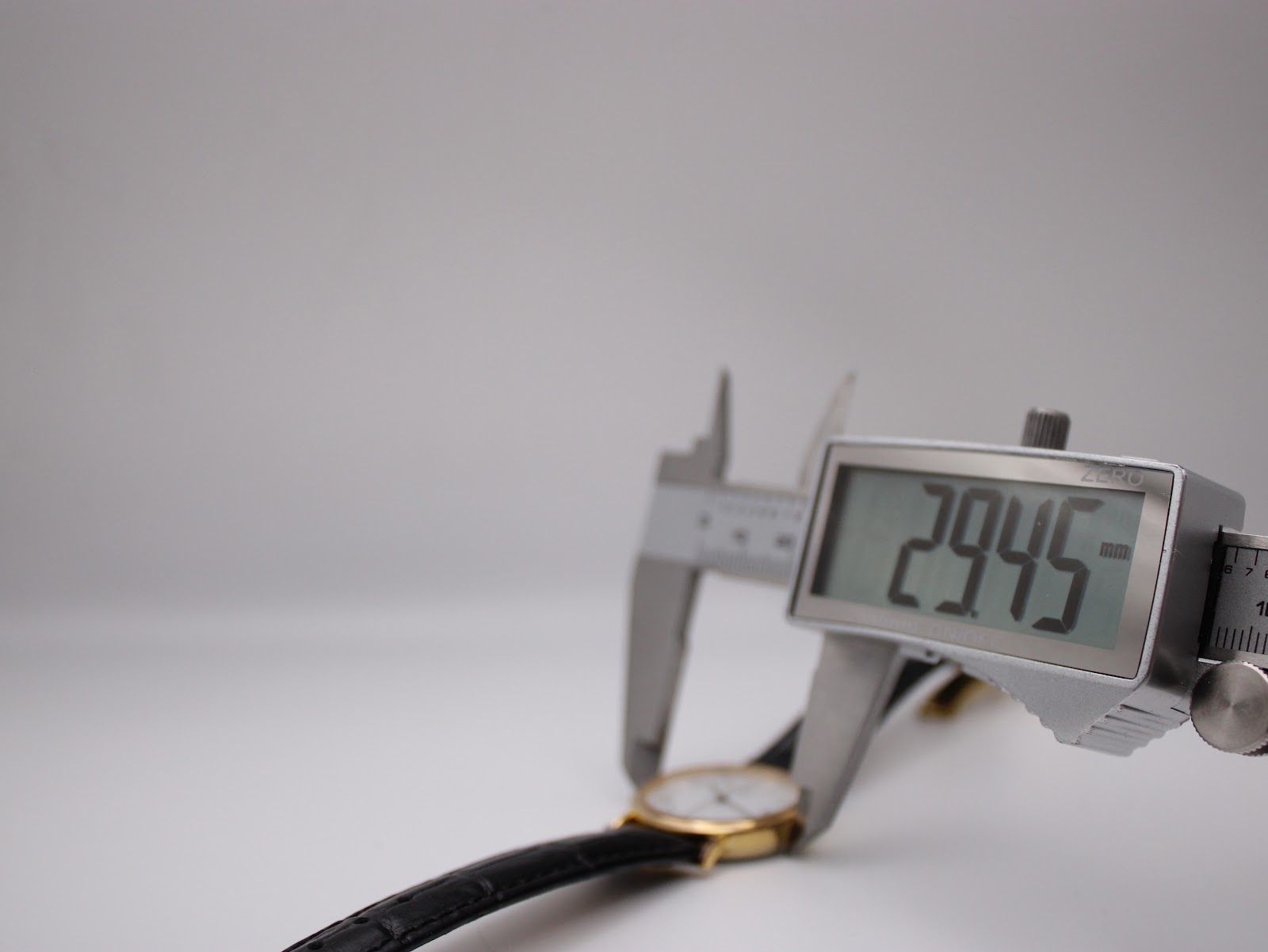 A digital caliper measuring the case diameter of the watch, displaying a precise reading of 29.45mm.