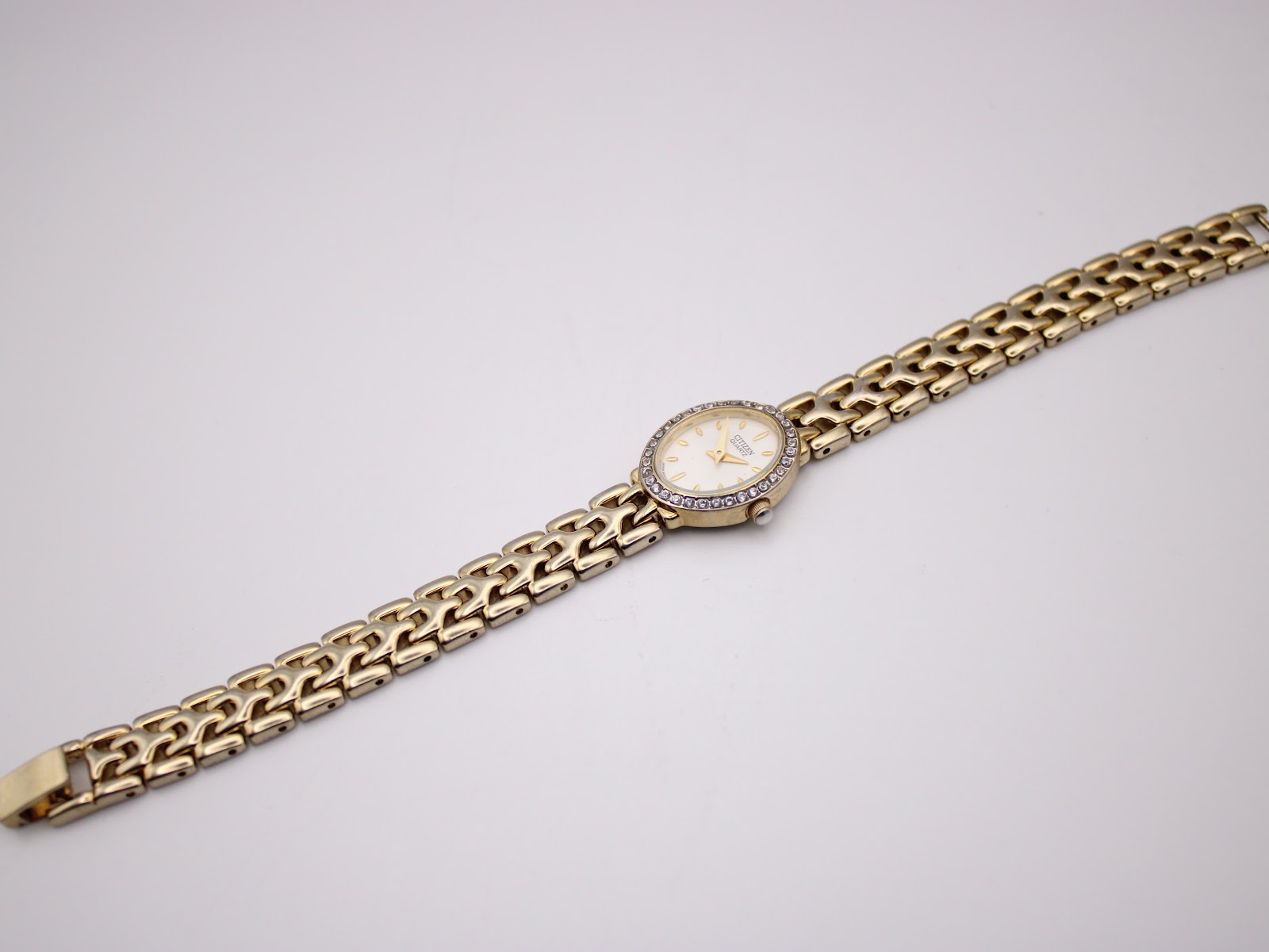 Overhead view of the full watch and integrated gold-tone steel bracelet laid flat, front side up.