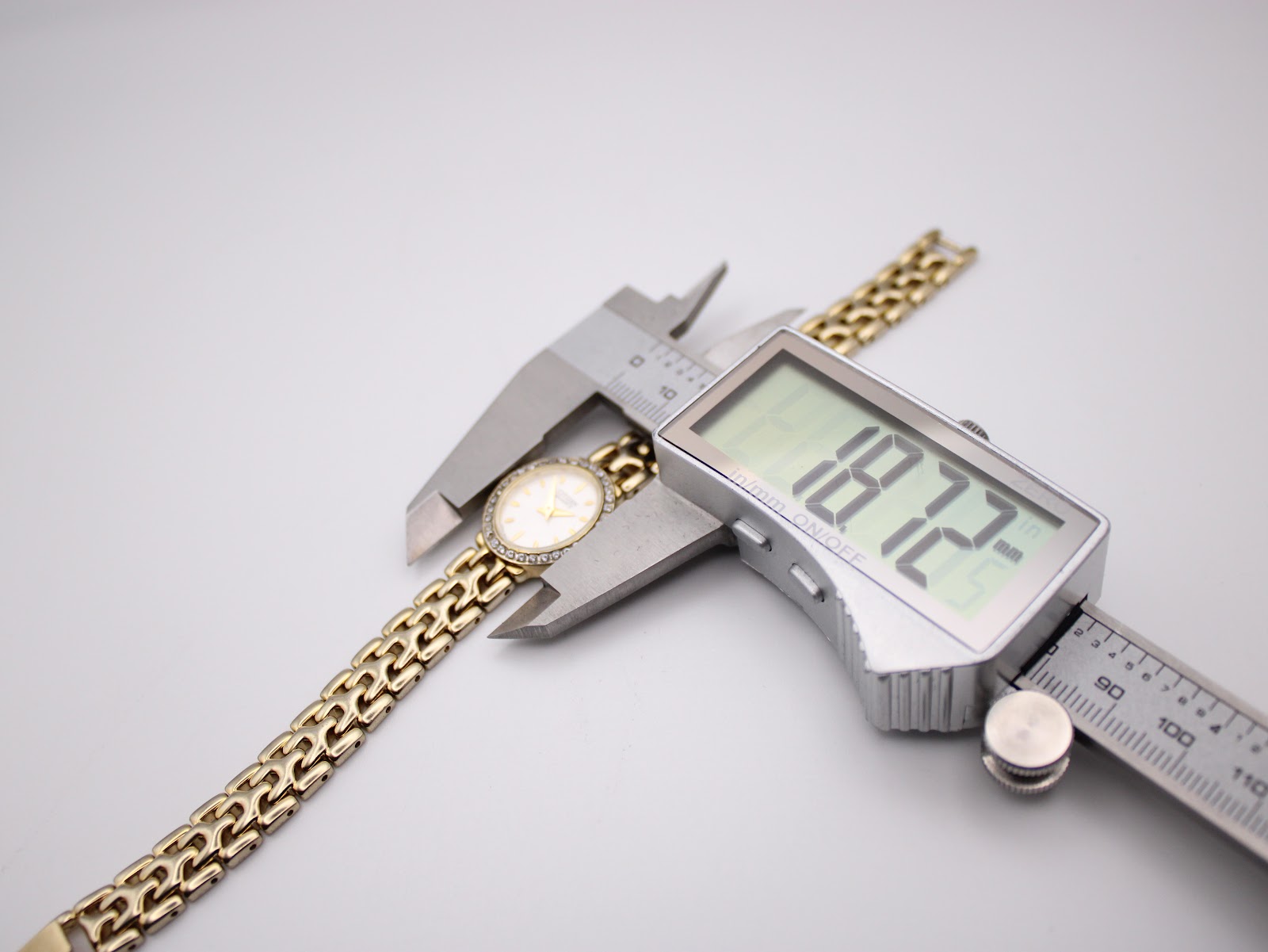 Digital caliper measuring the case diameter of the Citizen watch, displaying a precise reading of 18.72mm.