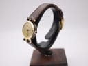 Angled side view of the Gucci 2000L watch on a stand, highlighting the black enamel side stripes and dark brown lizard grain strap.