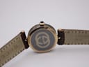 Close-up top-down view of the Gucci watch, revealing the iconic interlocking GG logo on the case back and embossed Gucci on the strap underside.