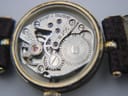 Macro photograph of the Swiss mechanical hand-wind movement inside the Gucci 2000L, showing the gears and 'SEVENTEEN 17 JEWELS' engraving.