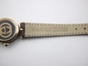Detailed view of the watch's dark brown leather strap, clearly showing 'GUCCI GENUINE LEATHER' embossed on the underside.