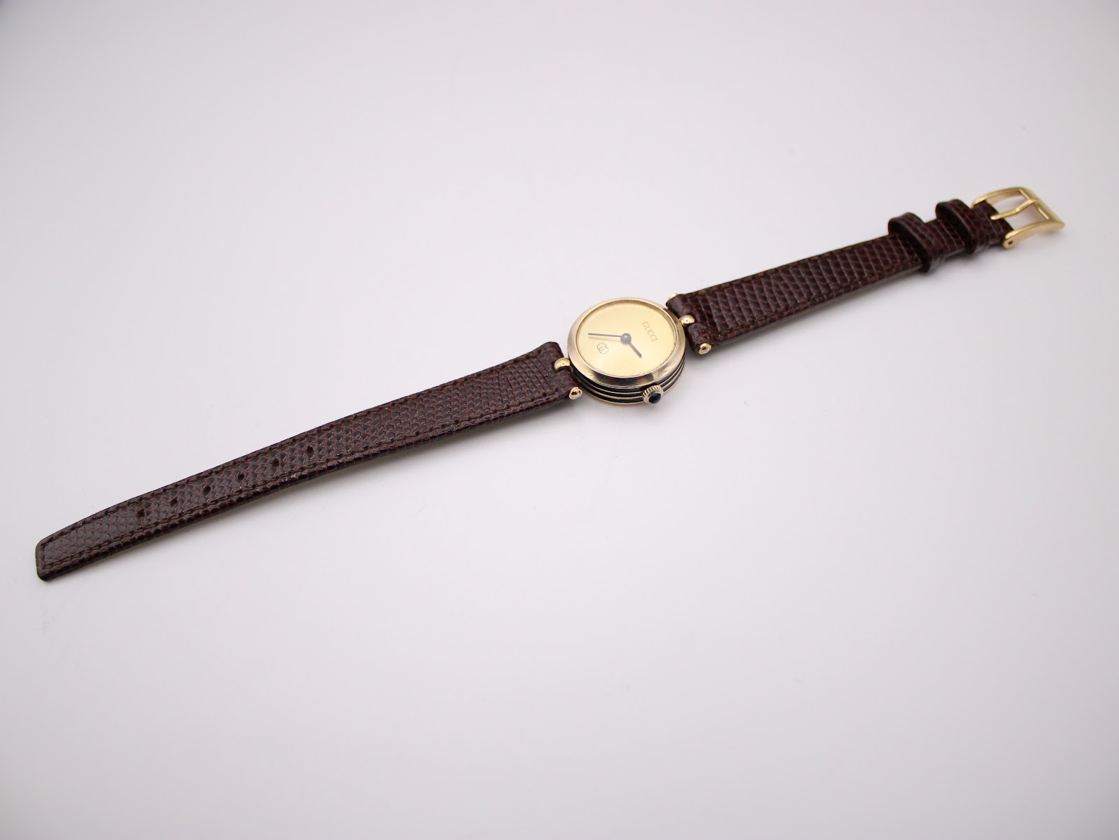 Slightly angled full view of the Gucci 2000L watch with the dark brown lizard grain strap laid flat.