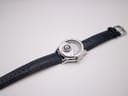 Overhead view of the Avon watch with the navy blue leather strap fully extended, showing the dial and buckle.