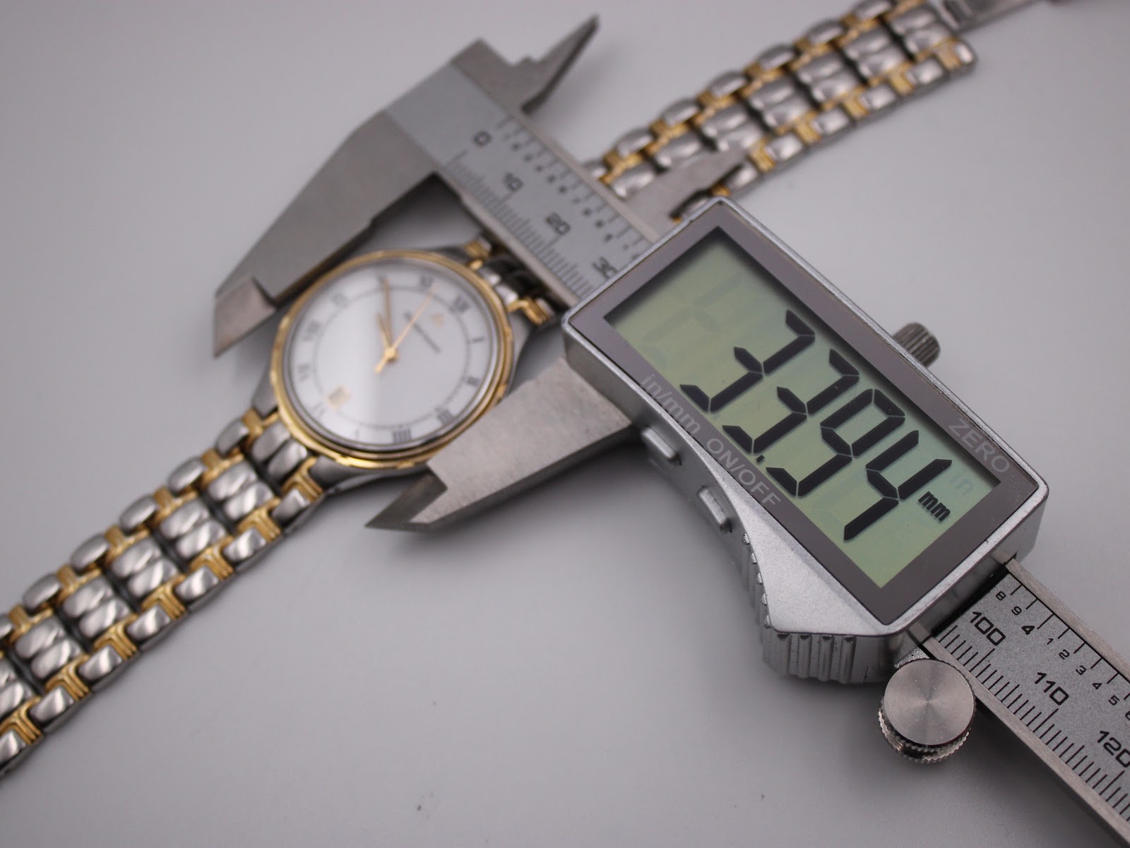 Digital caliper measuring the watch case diameter at 33.94mm, showing the two-tone bracelet.