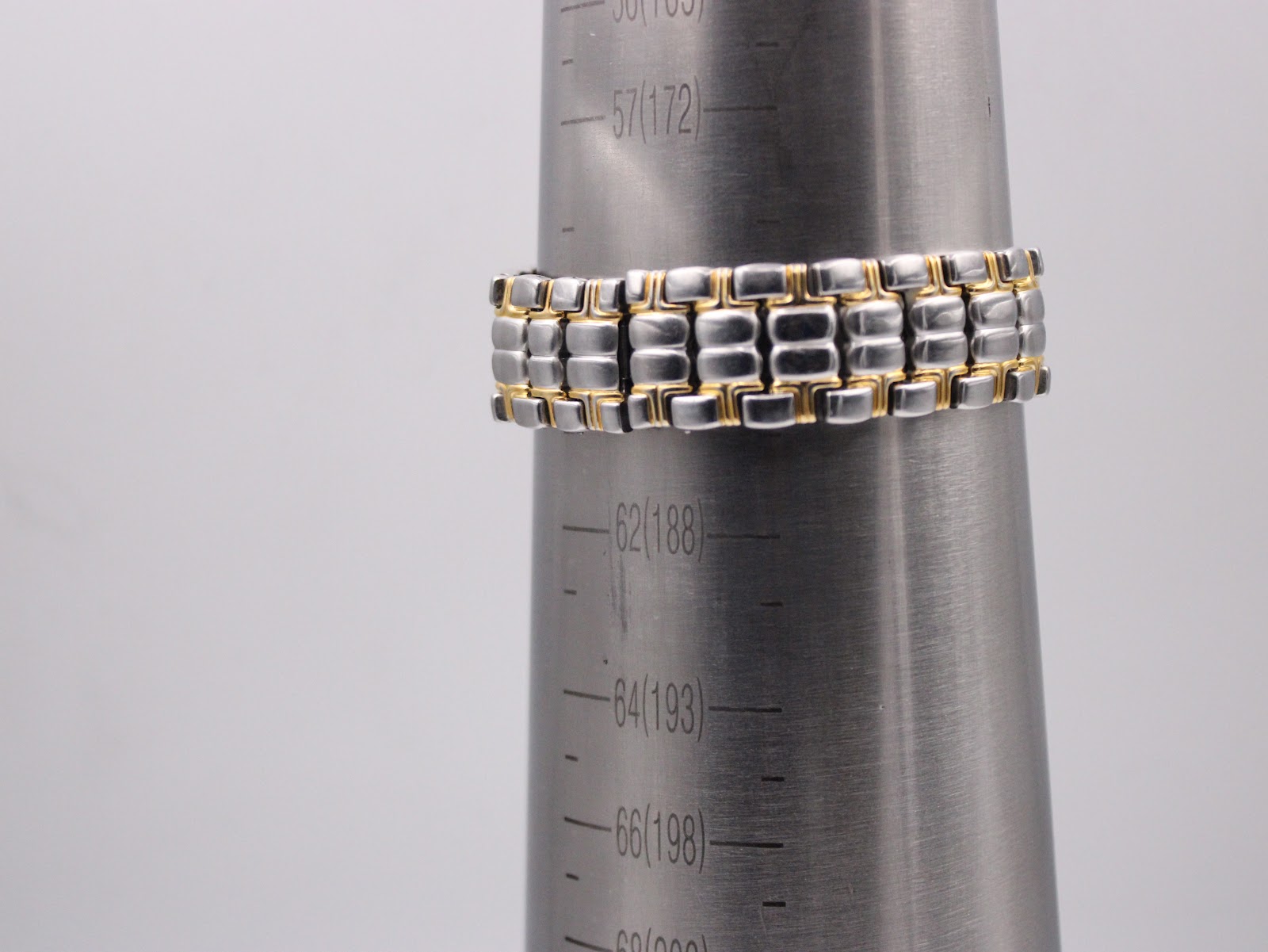 The two-tone bracelet displayed on a wrist sizing cone, indicating a fit up to 18.5cm.