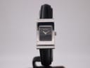Front view of the Gucci 2300L quartz watch with a black dial and silver rectangular case, on a display stand.