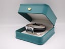 The Gucci 2300L watch resting inside a teal presentation box with a gold crown emblem.