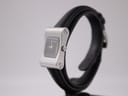 Angled view of the Gucci 2300L showing the right side of the silver rectangular case, crown, and black leather strap.
