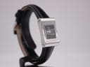 Angled view of the Gucci 2300L showing the left side of the silver rectangular case and black leather strap.