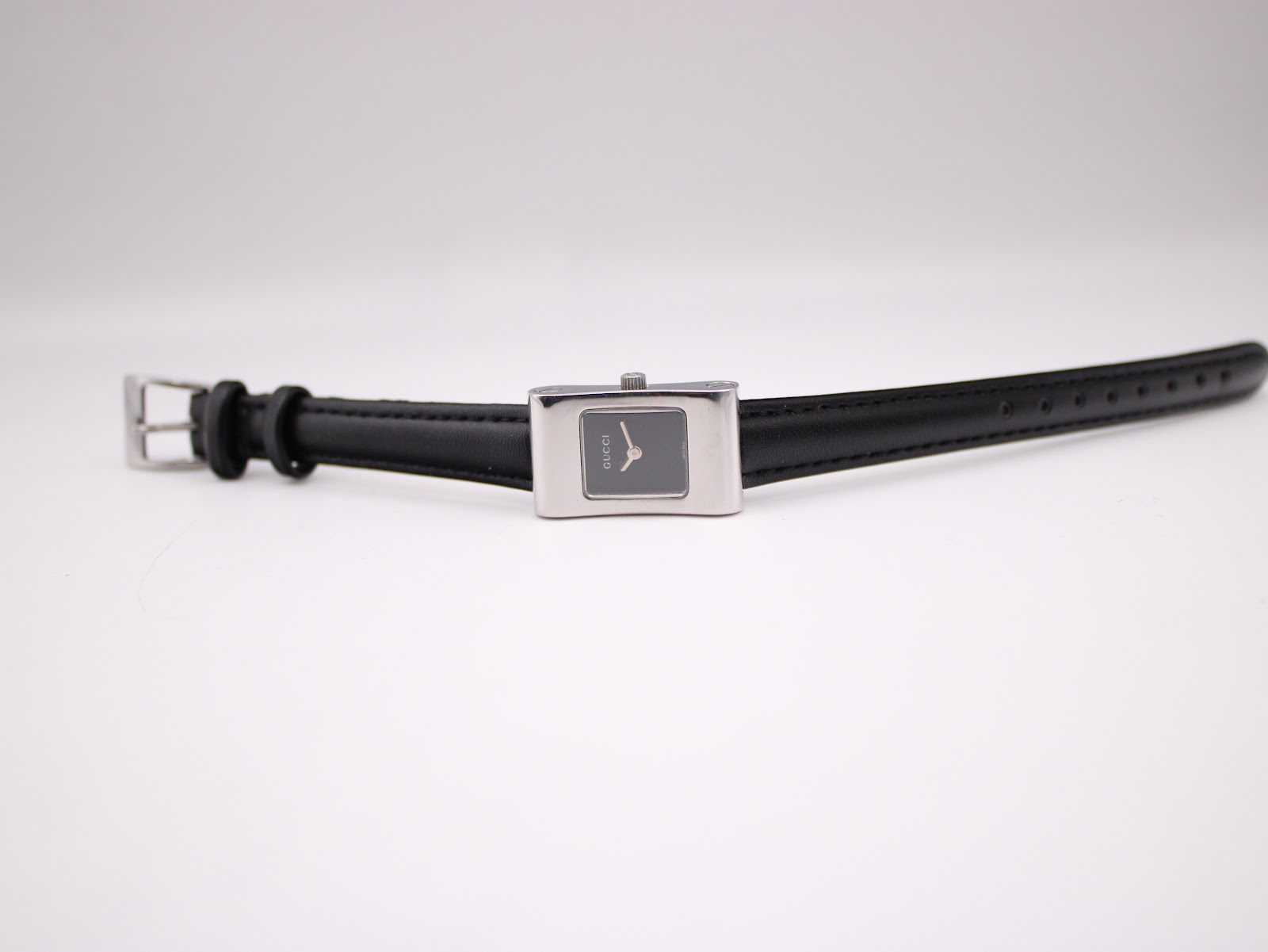 Top-down view of the Gucci 2300L watch laid flat, showing the full black leather strap and silver buckle.