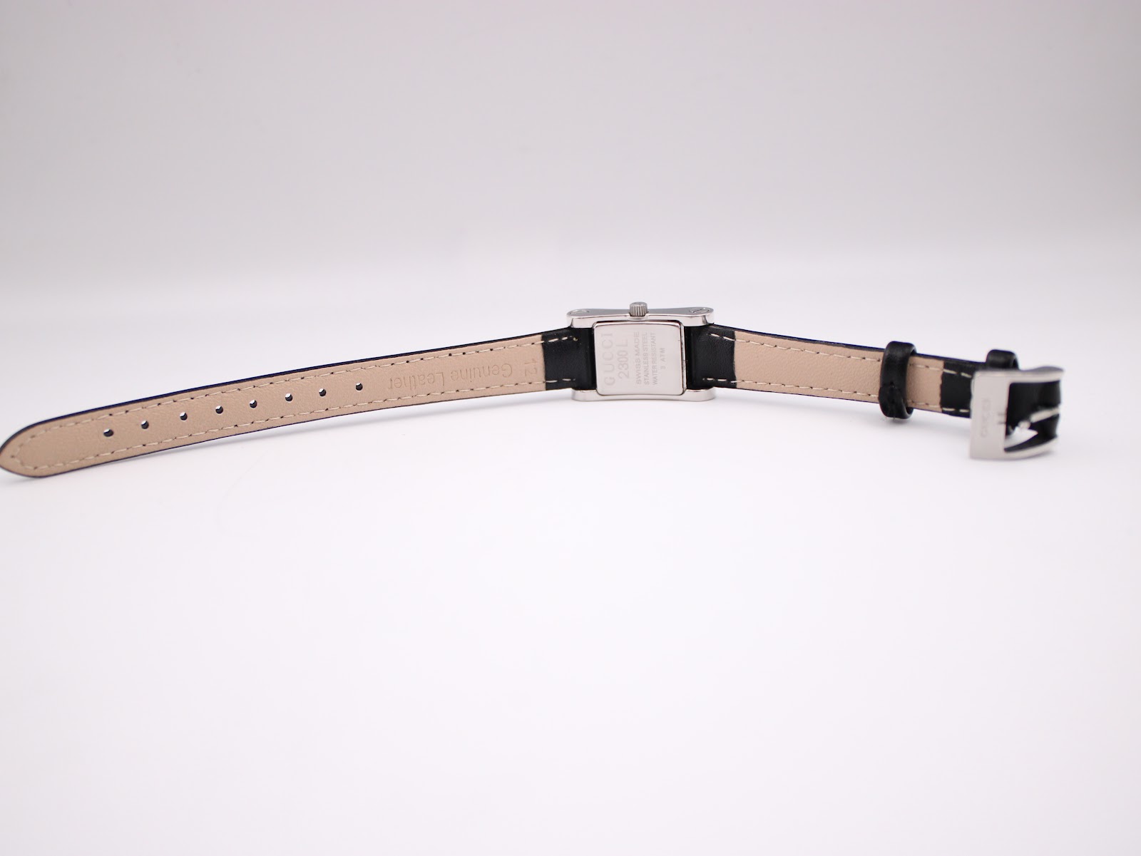 Bottom-up view of the Gucci 2300L watch laid flat, showing the cream underside of the genuine leather strap.