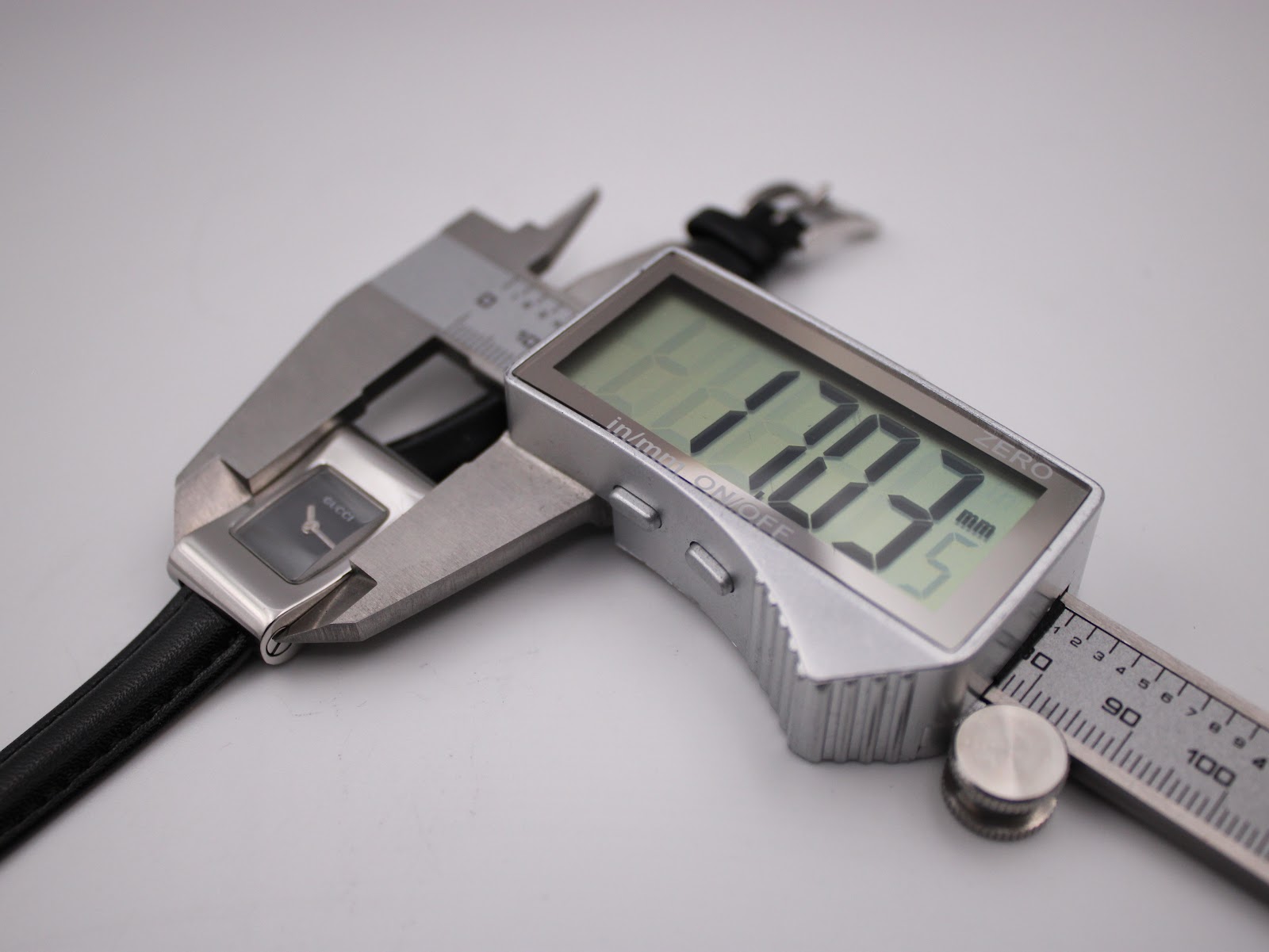 Digital caliper measuring the Gucci 2300L case width, displaying 17.03 mm.