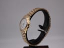 Side-angle view of the gold plated Rotary watch on a black display stand, showing the crown and case profile.