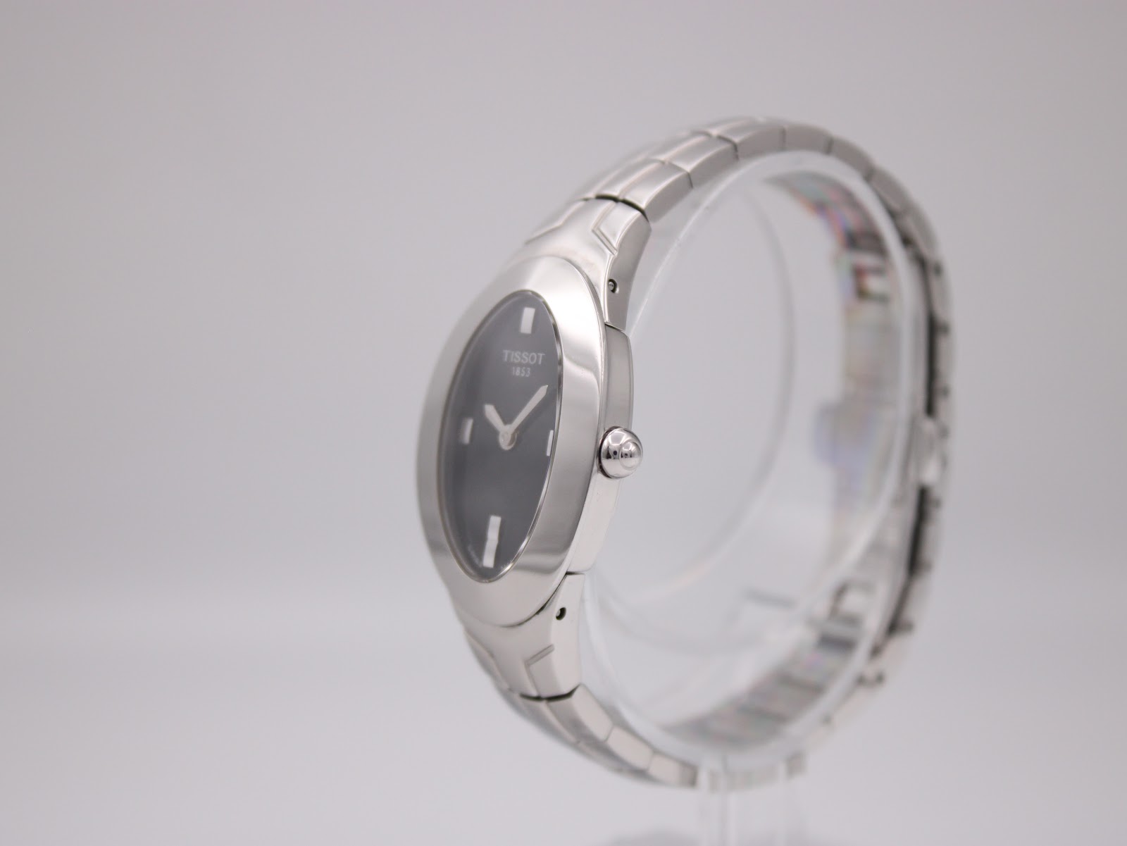 Side profile view of the Tissot L720 on a clear stand, highlighting the polished stainless steel case and bracelet links.