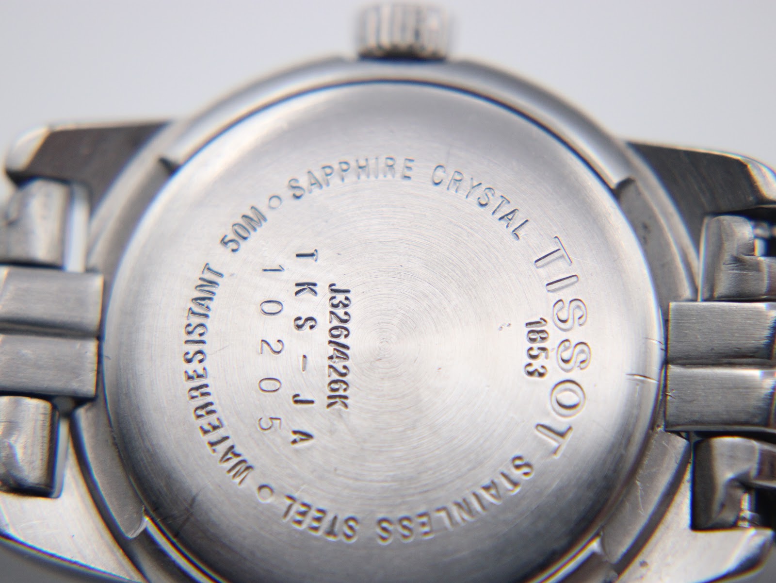 Close-up of the Tissot PR 50 stainless steel case back with model J326/426K, serial, 50m water resistant, and sapphire crystal engravings.