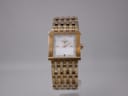 Front view of gold-tone Tissot L910 square watch with white sunburst dial and gold stick indices.