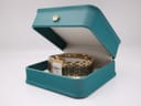 Tissot L910 gold-tone watch nestled in an open, teal-coloured watch box.