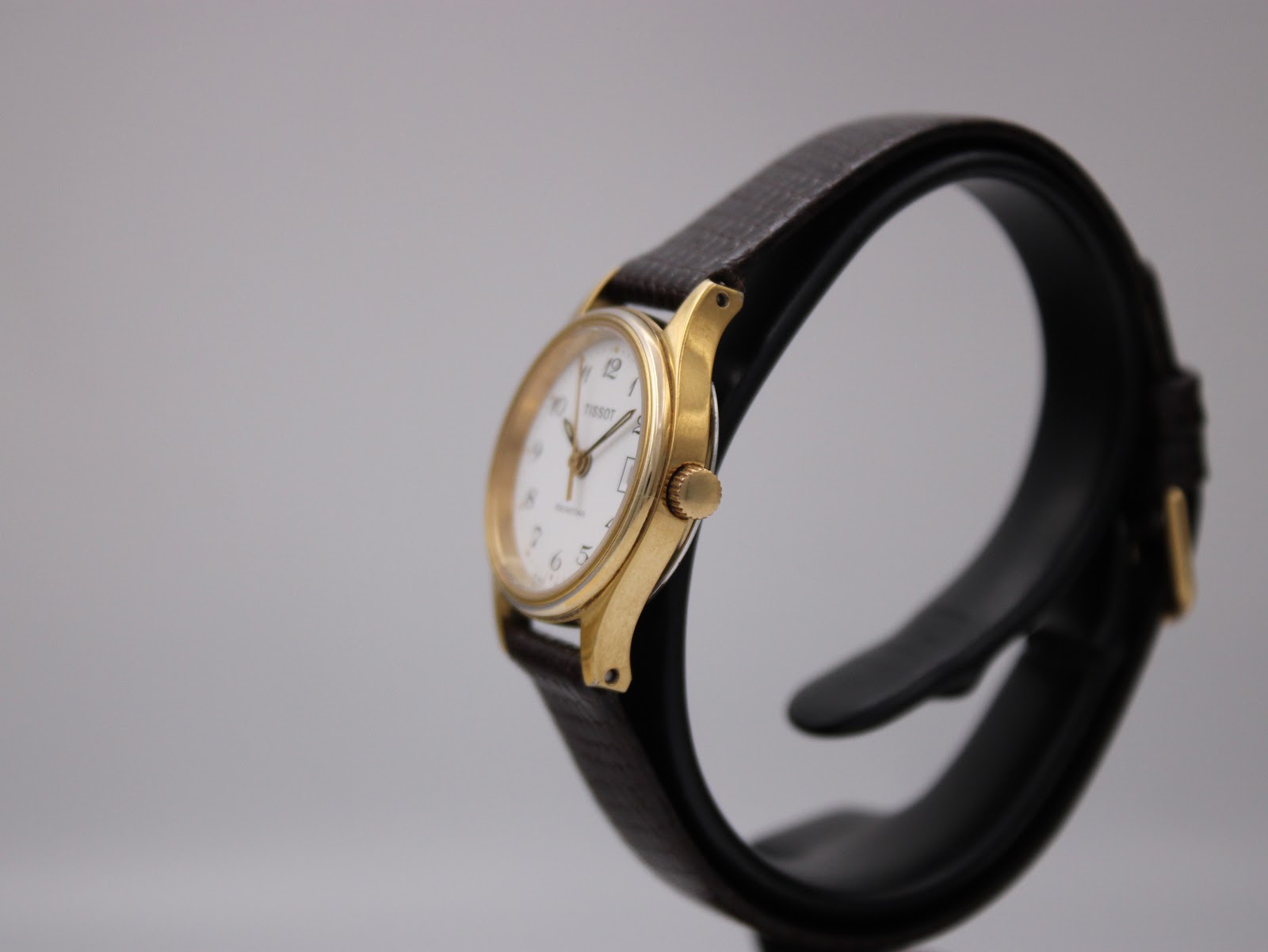 Right side view of the Tissot Seastar on a watch stand, showing the gold crown and case profile.