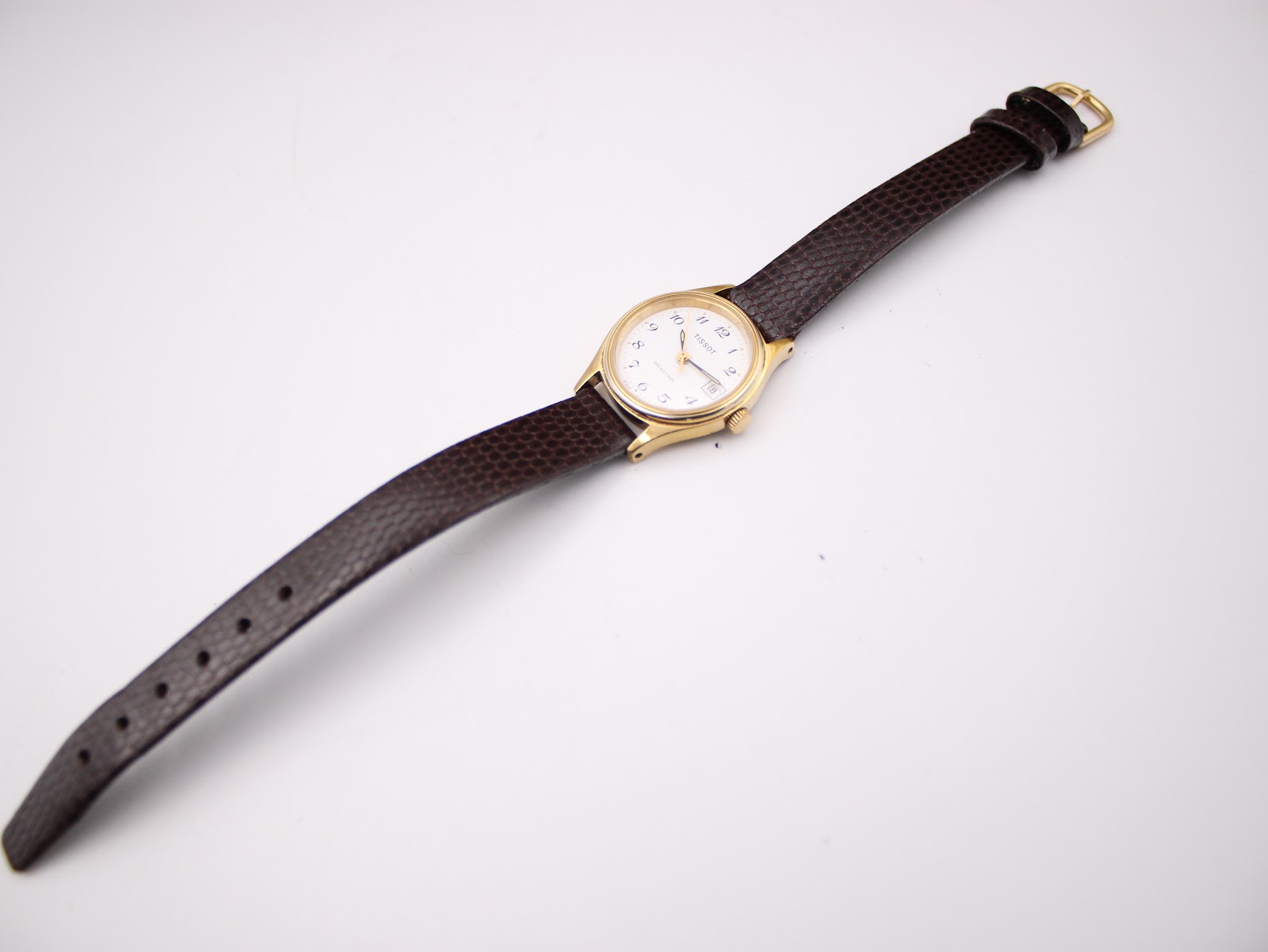 Top-down view of the Tissot Seastar watch laid flat, displaying the entire dark brown leather strap with gold buckle.