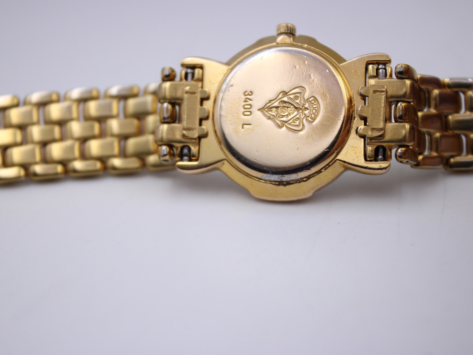 Close-up of the gold plated case back of the Gucci 3400L, showing the '3400 L' engraving and the embossed Gucci crest.