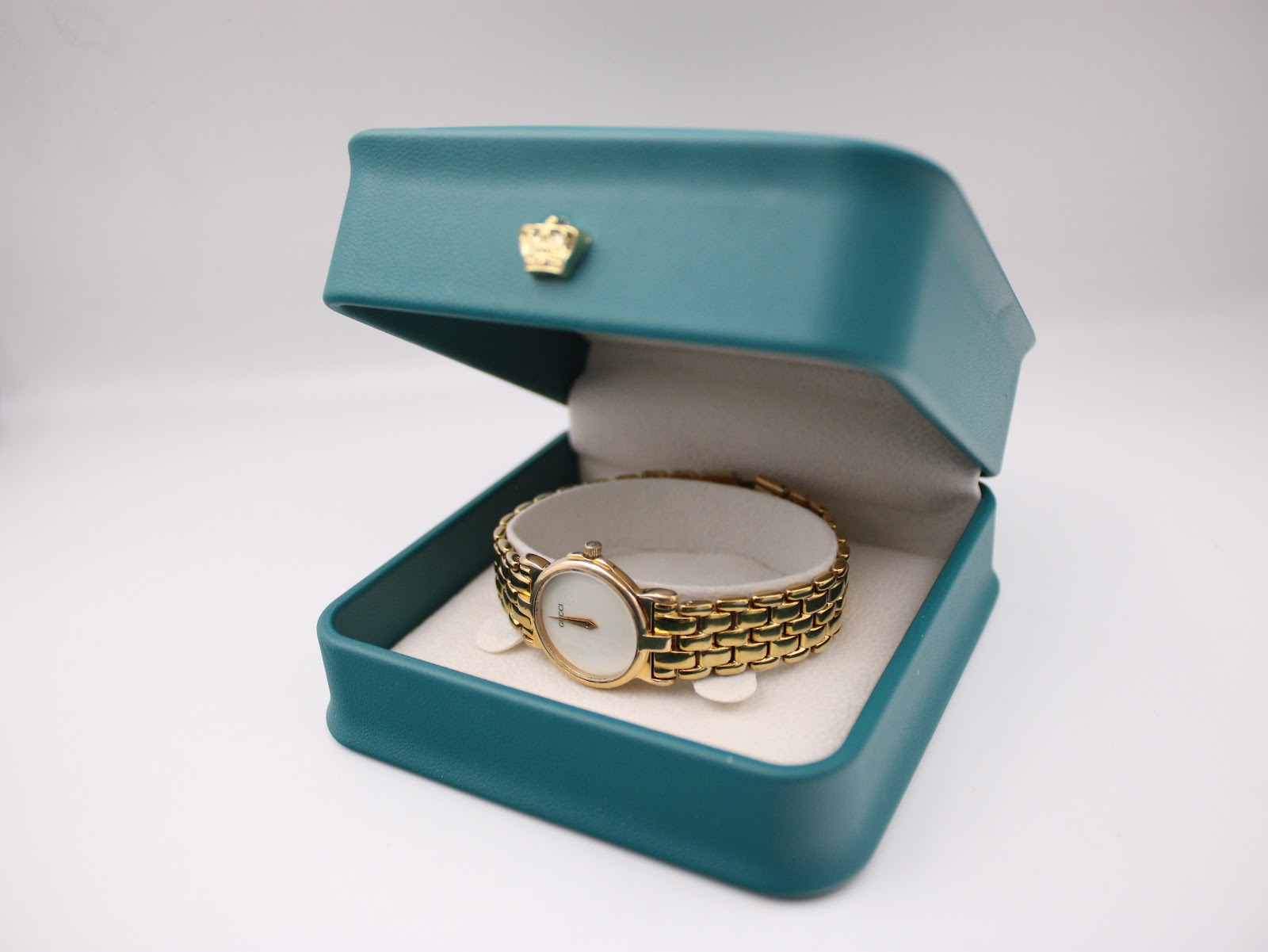 The Gucci 3400L watch resting open in a green presentation box, showcasing the watch and its non-original packaging.