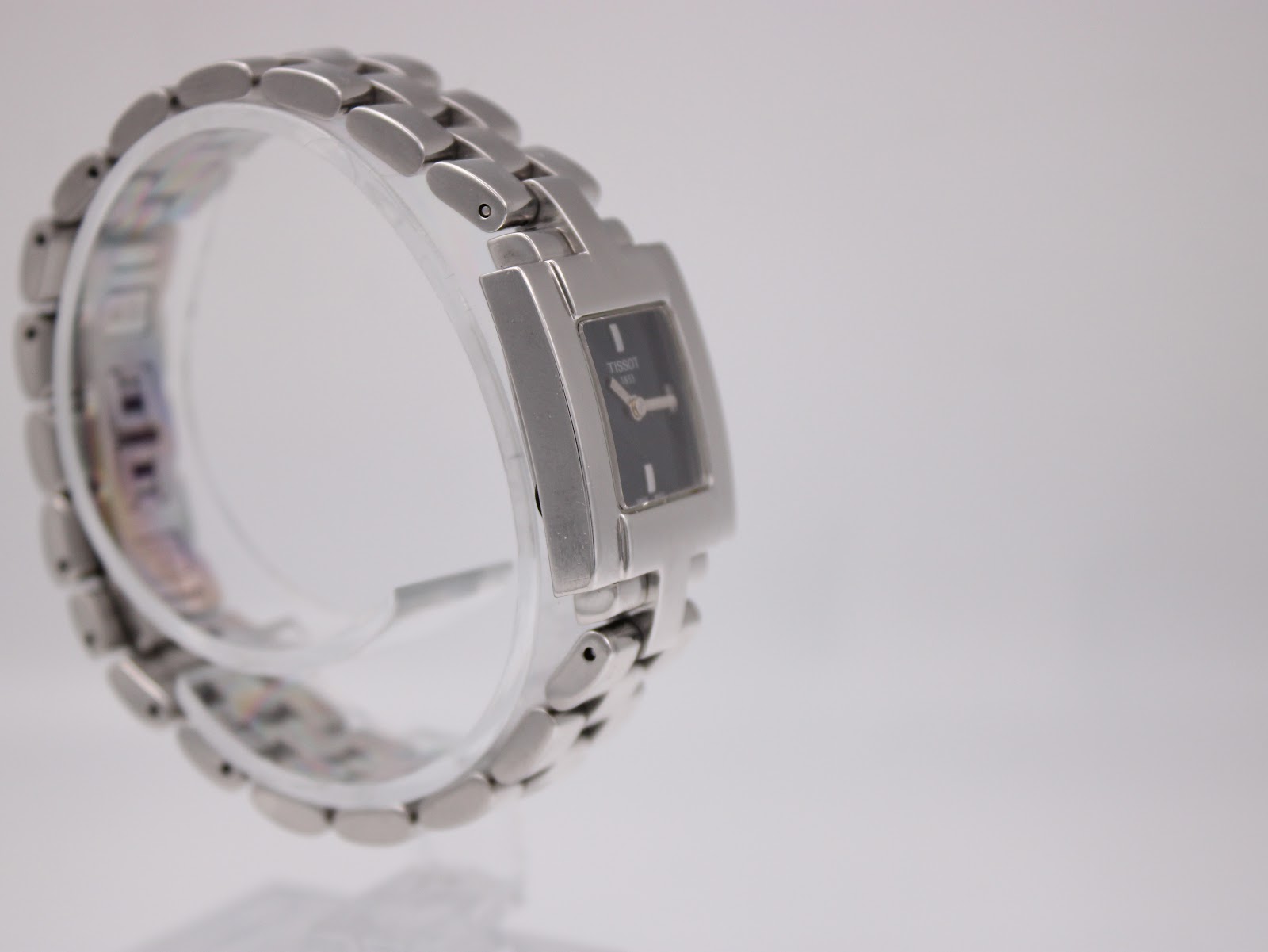 Left-side view of the Tissot T-Trend watch on a clear display stand, highlighting the integrated bracelet design and polished case.