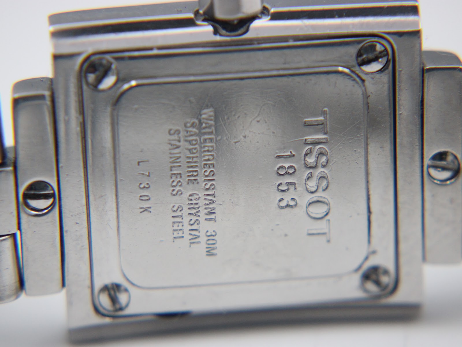 Close-up of the watch case back, engraved with "TISSOT 1853", "WATERRESISTANT 30M", "SAPPHIRE CRYSTAL", "STAINLESS STEEL", and "L 730 K".
