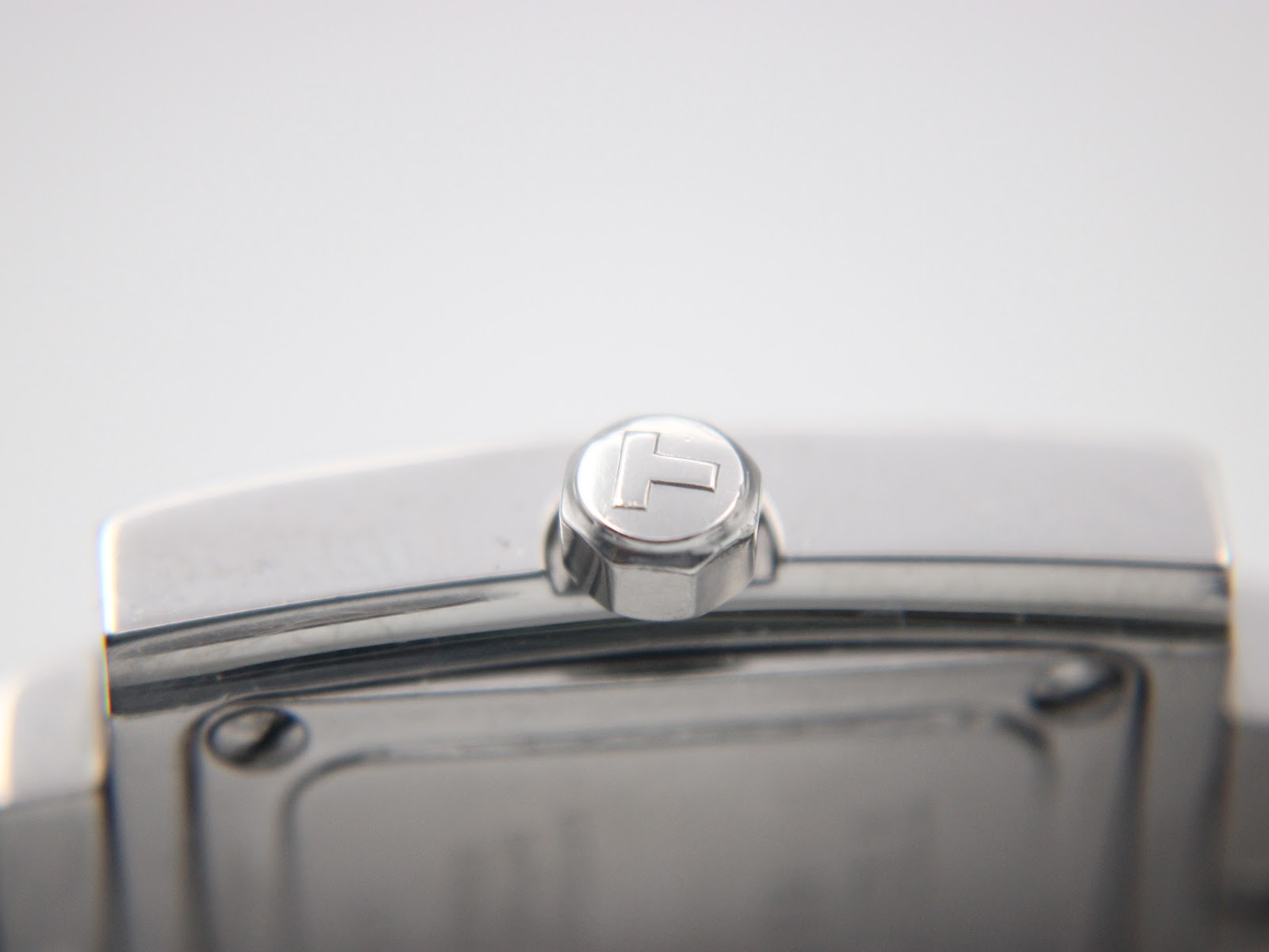 Macro shot of the polished stainless steel crown with the embossed Tissot "T" logo.