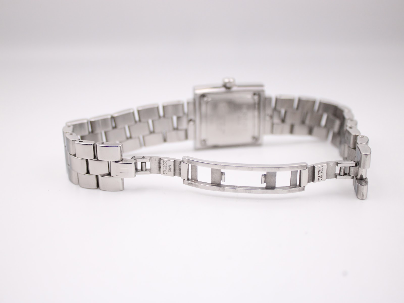 Close-up of the open hidden butterfly deployant clasp on the Tissot stainless steel bracelet, showing the "STAINLESS STEEL" engraving.