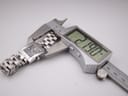 The Tissot watch case being measured by a digital caliper, displaying a precise width of 21.90mm.