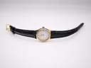 Top-down view of the Tissot watch laid flat, displaying the black leather strap and gold-tone buckle.