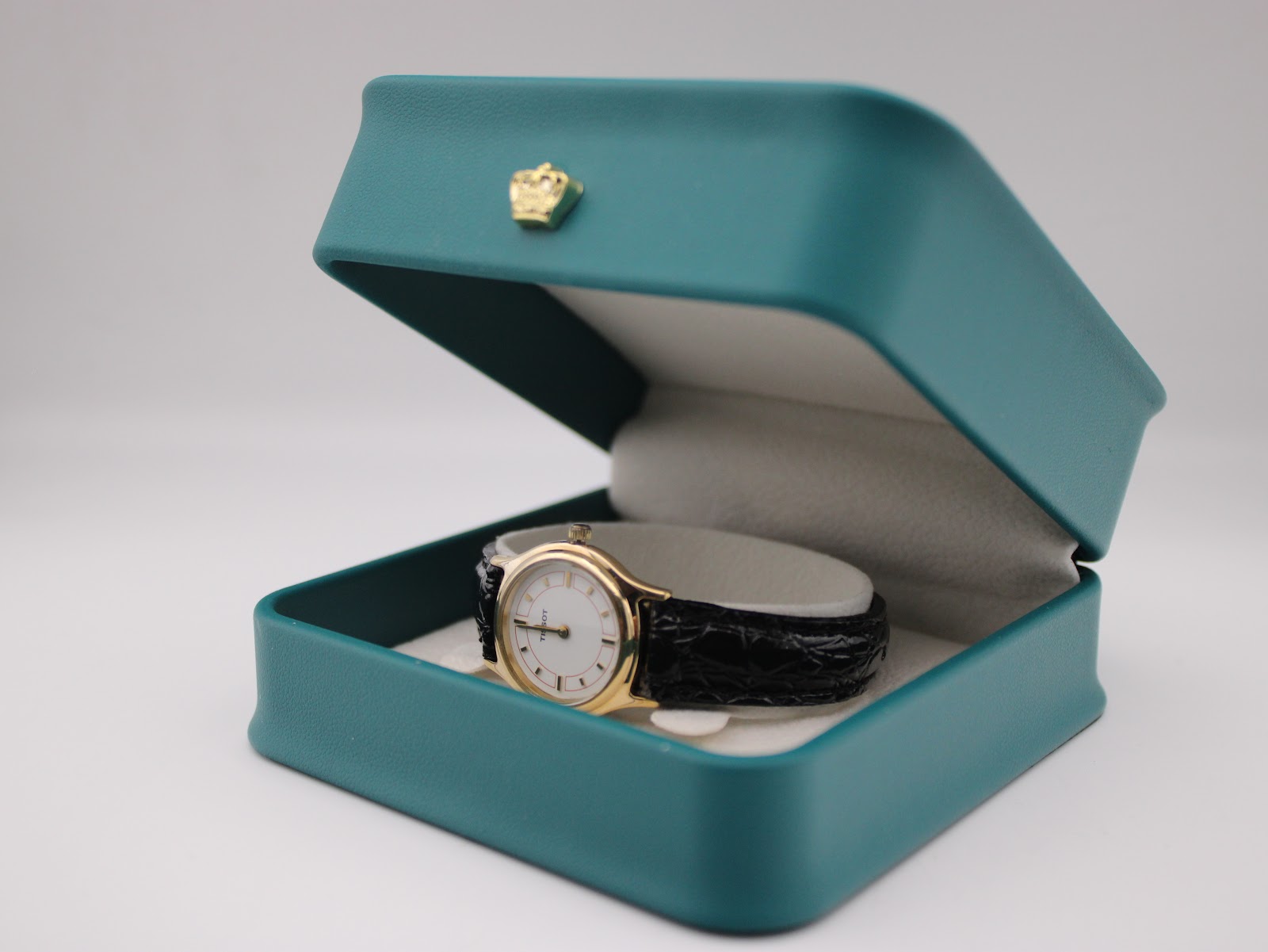 Tissot F300 watch displayed in an open teal presentation box with a gold crown emblem.