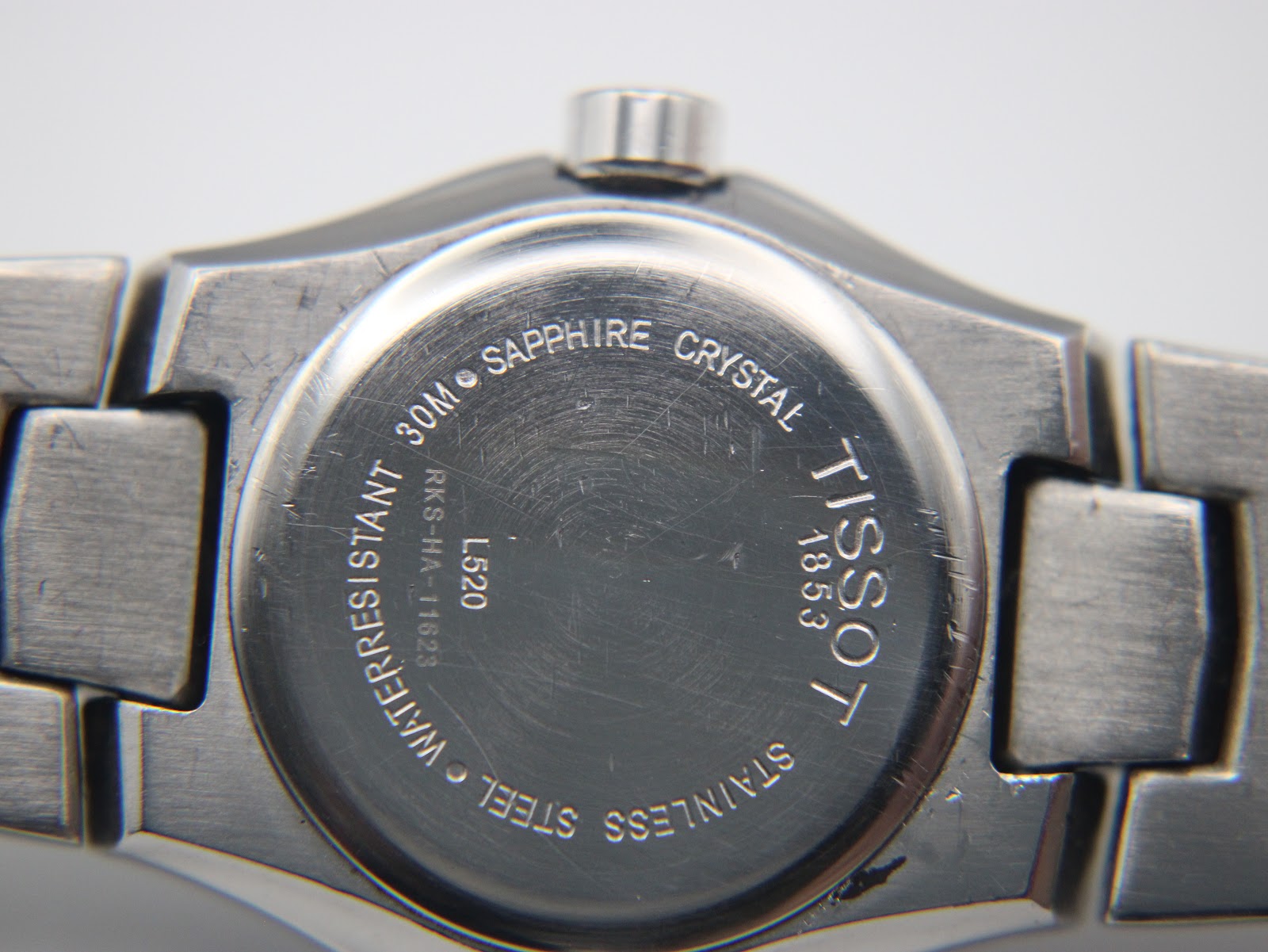 Close-up of the watch case back, showing 'stainless steel', 'sapphire crystal', '30m water resistant', and 'Tissot 1853' engravings.