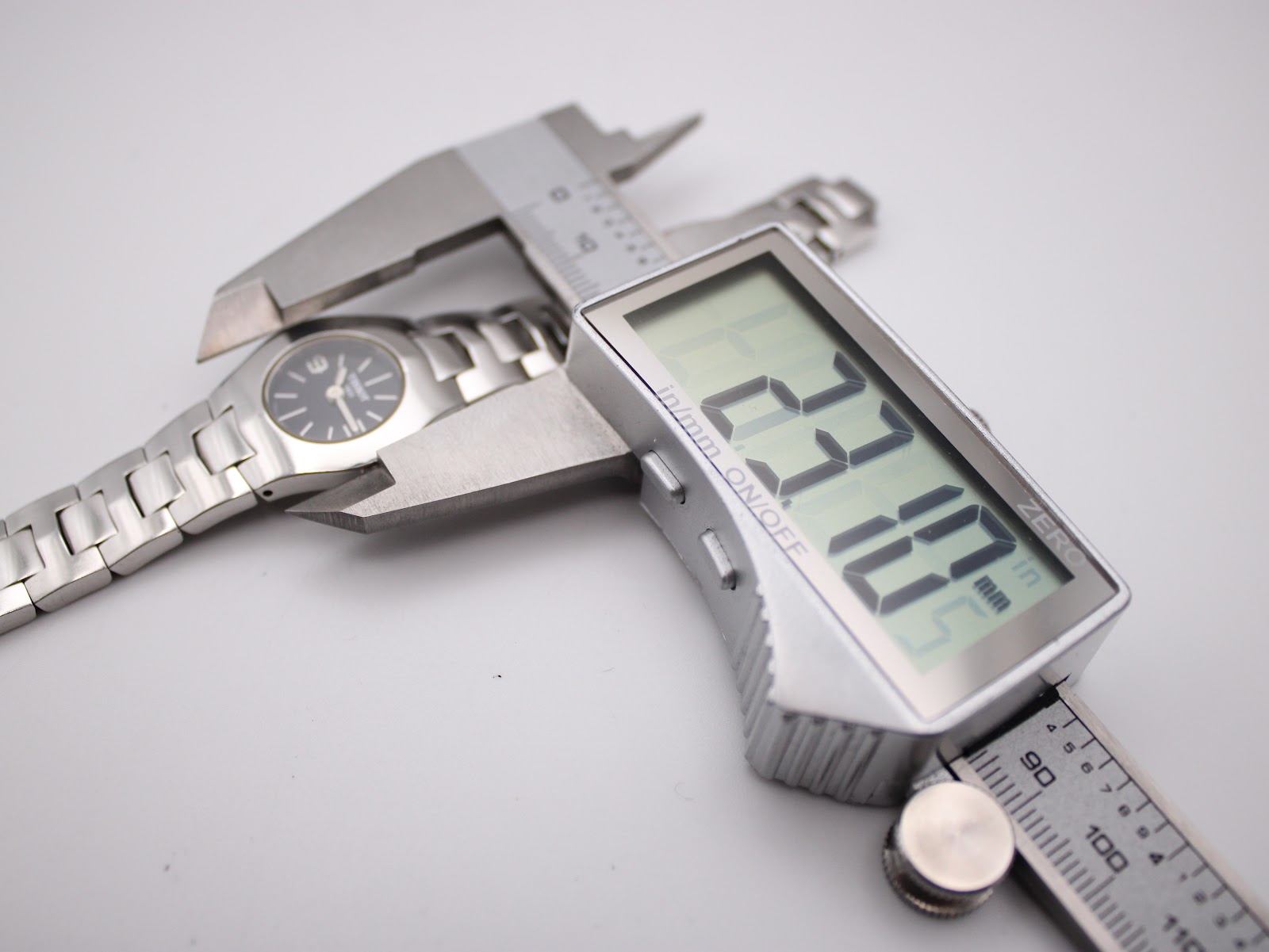 Digital caliper measuring the watch case diameter, displaying an exact measurement of 23.1mm.