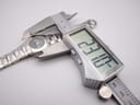 Digital caliper measuring the watch case diameter, displaying an exact measurement of 23.1mm.