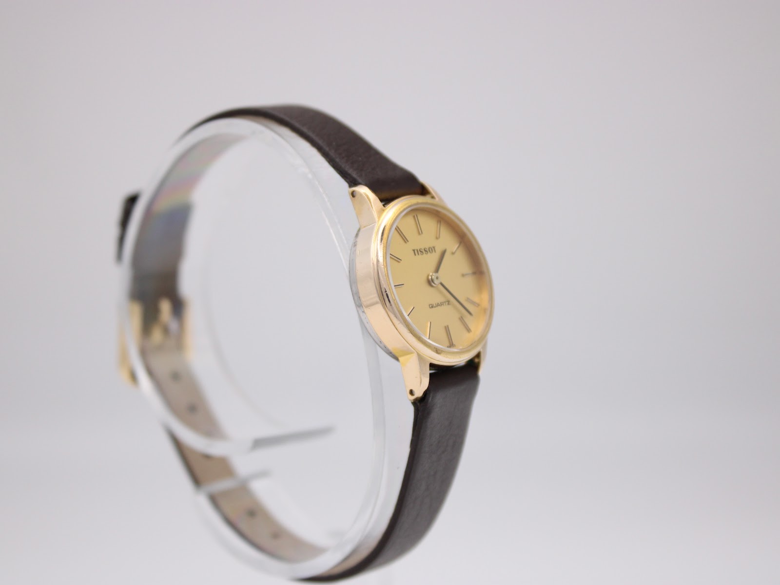 Another angled side view of the Tissot watch on a stand, showcasing the dial and case details.