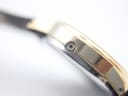 Extreme close-up of the hidden recessed crown on the side of the gold-plated watch case.