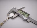 A digital caliper measuring the watch case, displaying a precise measurement of 23.22 mm in width.