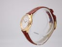 Side view of the Junghans watch on a clear stand, showing the gold-tone case and crown.